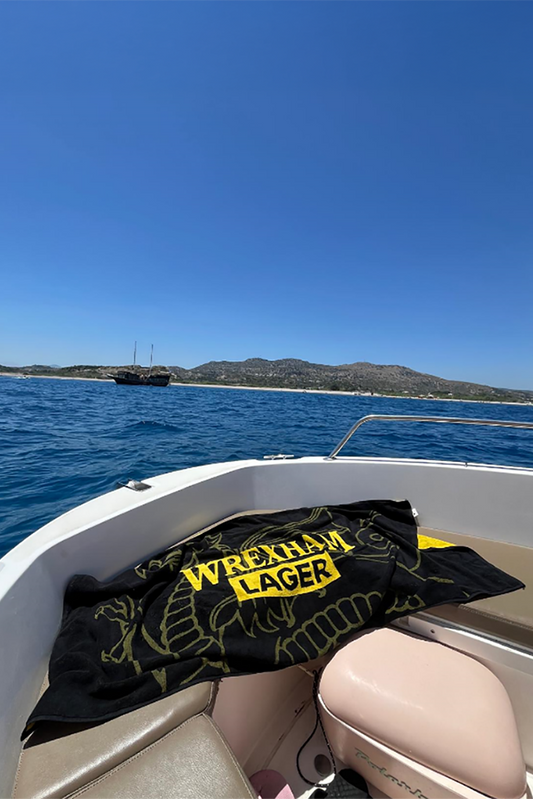 Wrexham Lager Beach Towel on bow of boat