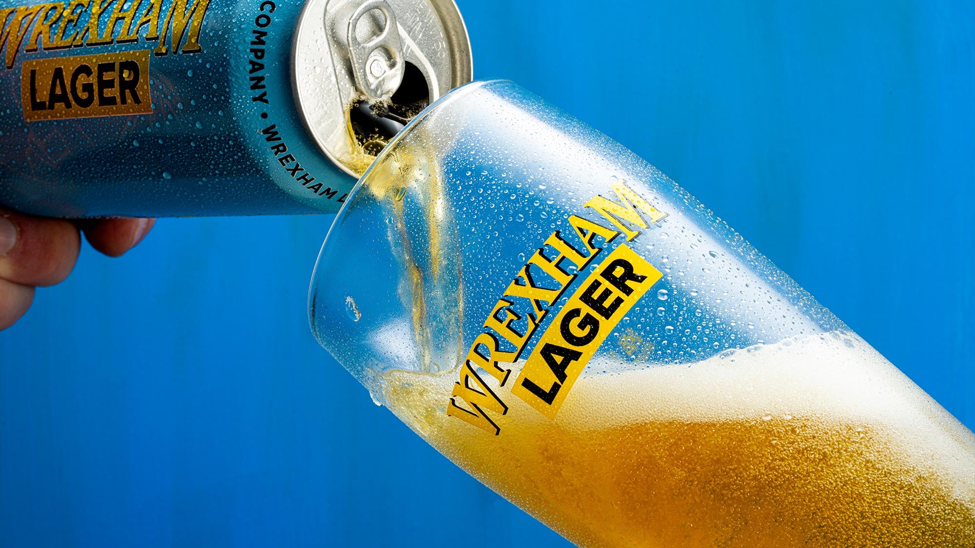 Wrexham Lager being poured into a glass with a blue background