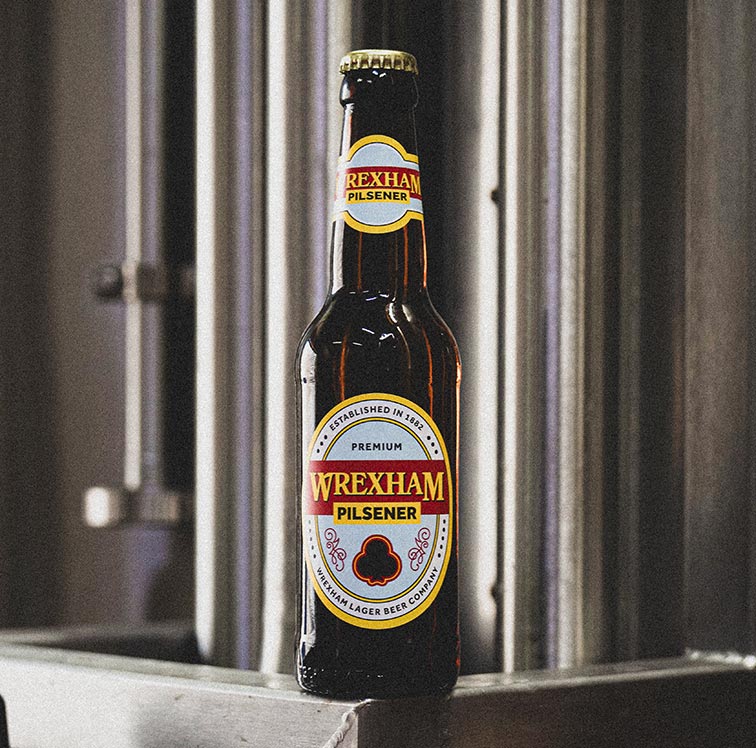 Wrexham Pilsener beer bottle on a metal surface with a blurred background