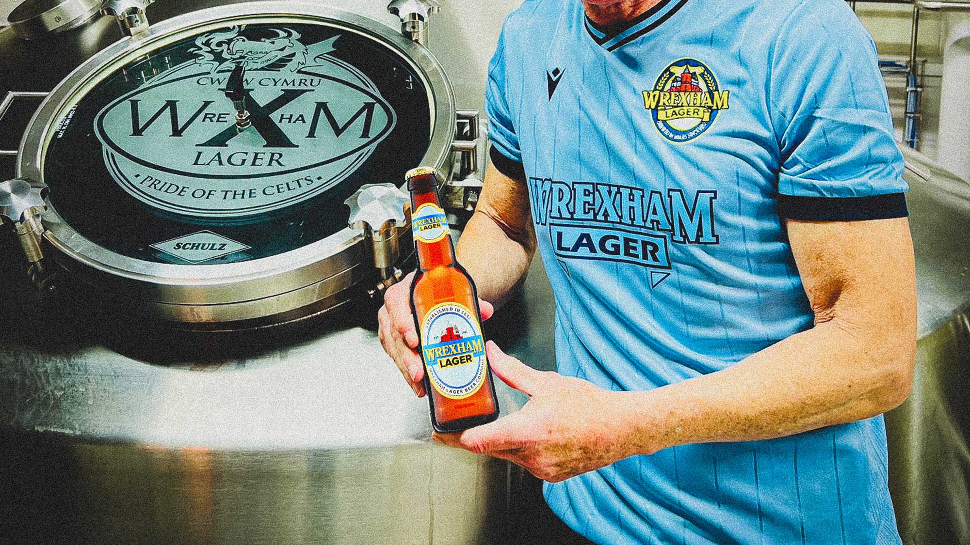 Man in Wrexham t-shirt holding Wrexham lager